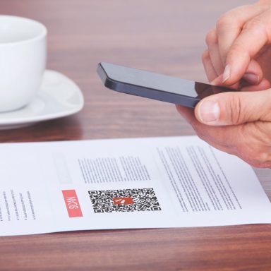 Mit einem Smartphone wird ein QR-Code auf einem Blatt Papier gescannt.